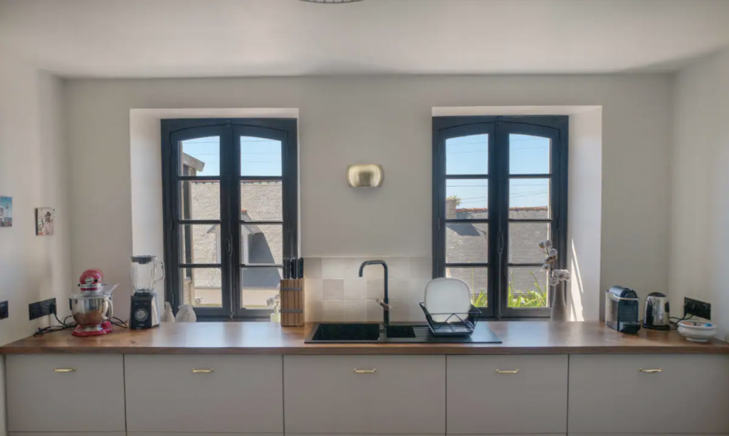Cuisine d'une maison en blanc et bois, avec deux fenêtres