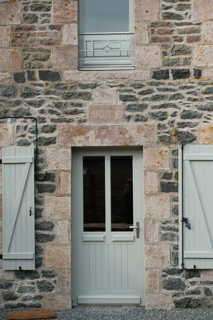 Une porte vert d'eau sur une face de maison en pierres